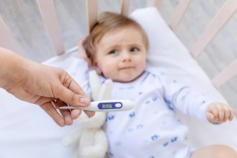 Thermometer in focus in mom's hands with a normal temperature of 36.6 degrees 스톡 사진