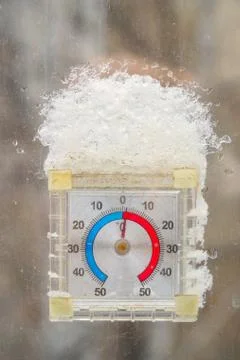 Thermometer in the form of a clock outside window with a snow cap Stock-Fotos
