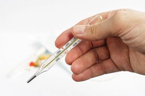 Thermometer in hand, thermometer and tablets, analog fever thermometer. Stock Photos