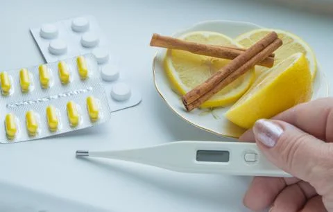 The thermometer in the hands, tablets, lemon with a cinnamon treatment Foto stock