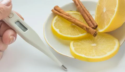 The thermometer in the hands, tablets, lemon with a cinnamon treatment Foto stock