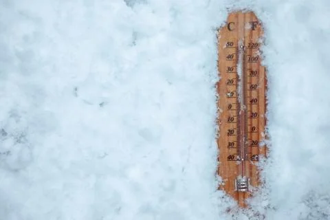Thermometer lying on layer of ice and  showing low temperature Stock Photos
