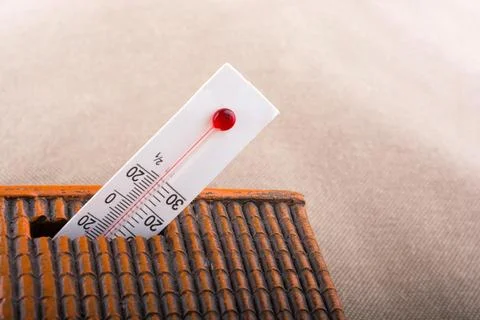 Thermometer measuring high temperature placed on a little model house Foto stock