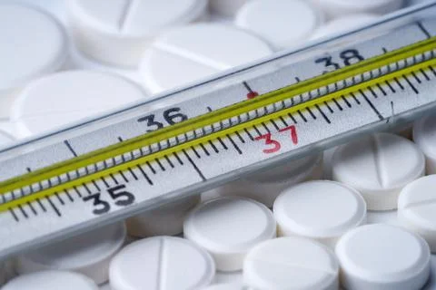 Thermometer for measuring temperature on white tablets. Stock Photos