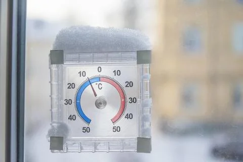 Thermometer with negative temperature and fresh snow on a window Stock Photos