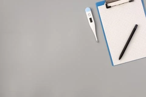 Thermometer, notepad and pen on gray background, health care concept and prev Stock Photos
