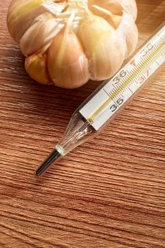 The thermometer is on the table in the background of garlic Stock Photos