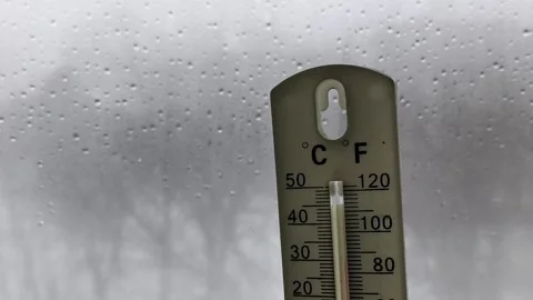 Thermometer in a womans hand against the background of a window with raindrops Stock Footage 326735295