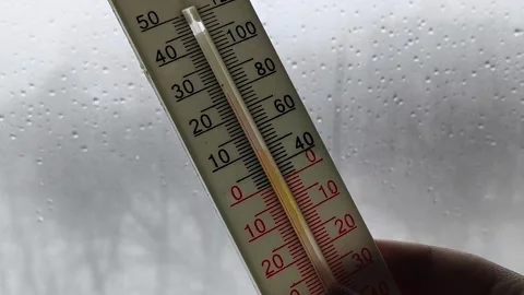 Thermometer in a womans hand against the background of a window with raindrops Stock Footage 326735333