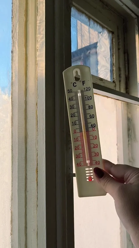 Thermometer in a womans hand against the background of an old wooden window with Stock Footage 327457057
