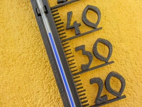 Thermometer in yellow wall measuring external air temperature over forty cels Stock Photos
