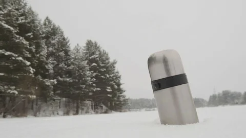 Thermos in the snow against the background of falling snow Stock Footage 124045988