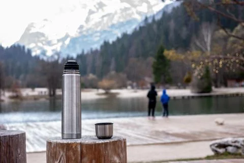 Thermos on stump and two wlaking kids silhouettes Stock Photos