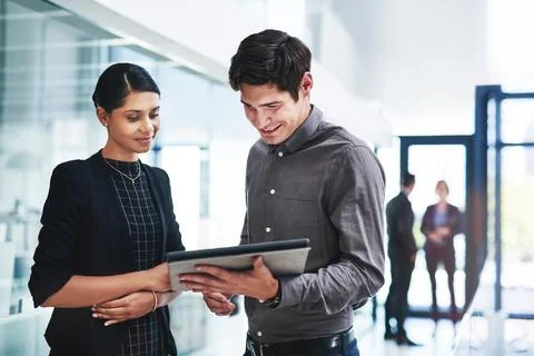 These are really pleasing figures we have here. two young businesspeople using a Stock Photos