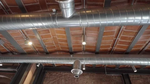 These exposed pipes often feature circular air diffusers for ventilation in Vidéo 336522669
