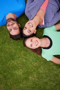They are inseparable. High angle shot of a three friends lying down on grass. Stock Photos