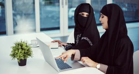 They enjoy working together. two young arabic businesswomen working on a laptop Stock Photos