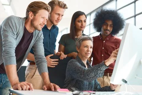 They get it done every time. a group of creative designers hard at work in their Stock Photos