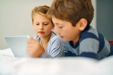 They love their toons in the morning. an adorable little girl and boy using a Stock Photos