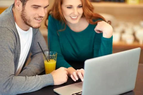 They share the same interests. Shot of a young couple using a laptop while ha 写真素材