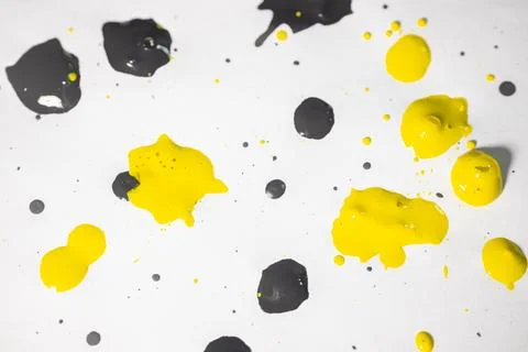 Thick and shiny splashes of black and yellow paint scattered. Stock Photos