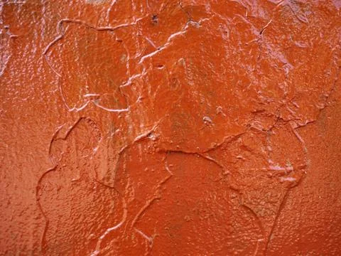 Thick and uneven layer of red paint on a wall closeup Stock Photos