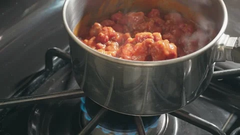 Thick beef chili simmering in a pot on gas stove Stock Footage 339532248