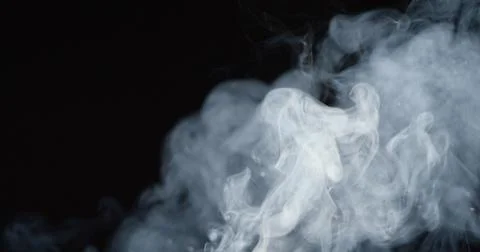 Thick billowing clouds of smoke over dark background Stock Photos