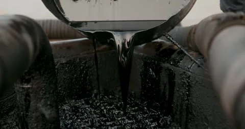 Thick, black petroleum liquid is poured from a metal container into an 스톡 동영상 346317356