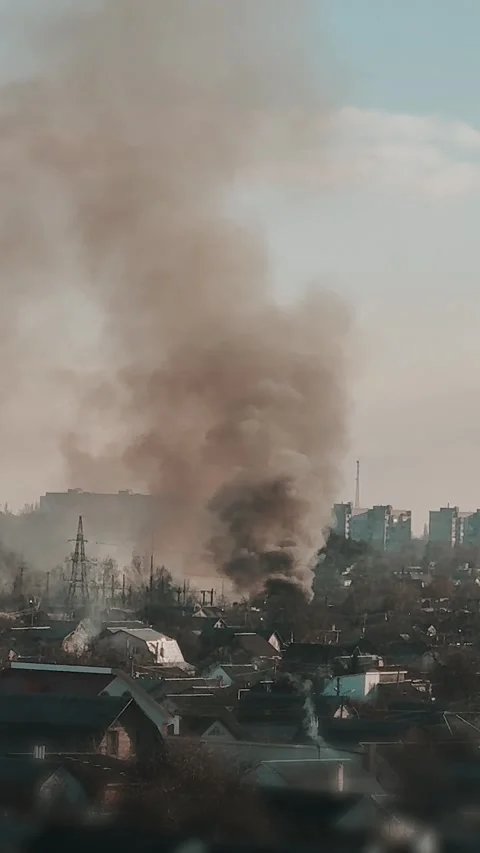 Thick black smoke rises into the sky from a burning building in the city Stock Footage 327301987