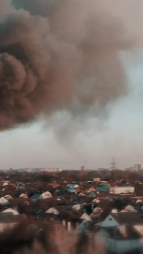 Thick black smoke rises into the sky from a burning building in the city Stock Footage 327301992