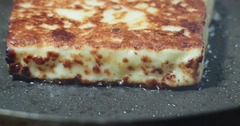 A thick block of halloumi cheese pan fries to a golden brown 動画素材 335325184