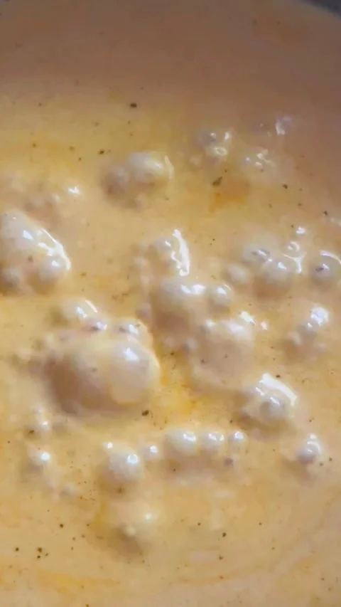 Thick, bubbling creamy orange sauce or soup simmering in a pan Видео 346411073