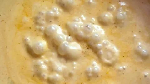 Thick, bubbling creamy orange sauce or soup simmering in a pan Видео 346456814