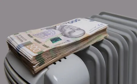 Thick bundle of large bills of Ukraine lies on the heating radiator Stock Photos