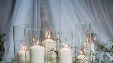 Thick burning candles standing in transparent vases surrounded by textiles Stock Footage 97722382