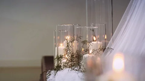 Thick burning candles standing in transparent vases surrounded by textiles Stock-Footage 97722424