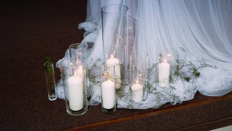 Thick burning candles standing in transparent vases surrounded by textiles Stock Footage 97722532