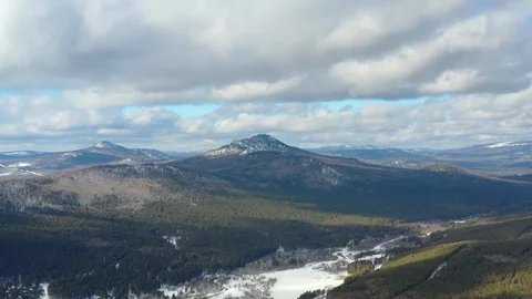 Thick clouds float over the snowy mountains and pine forest Stock Footage 126232589