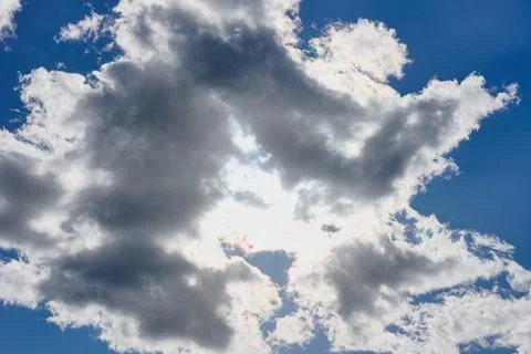 Thick clouds move across the sky while sunlight breaks through in an afternoo Stock Photos