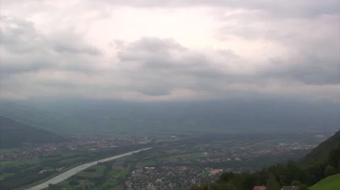 Thick clouds moving over wide river valley in Alps Stock Footage 49769259