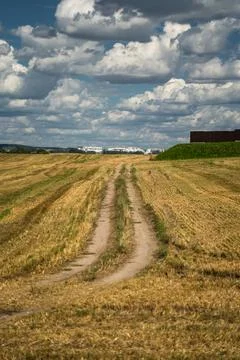 Thick clouds over a dirt road in a field. The road to the field after harvest Stock Photos