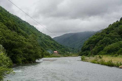 Thick clouds over the mountains, a river between the mountains Stock Photos