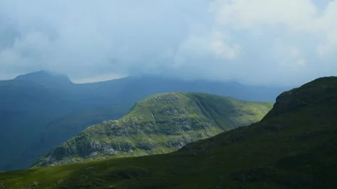 Thick clouds racing over covered mountaintop of Scafell with cloud shadows Stock Footage 278450394
