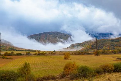 Thick clouds slide down from the mountains and are swirled by the wind. Autumn Stock Photos