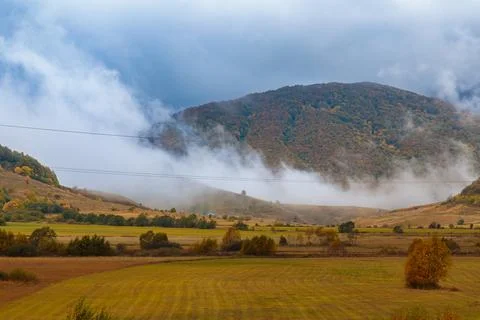 Thick clouds slide down from the mountains and are swirled by the wind. Autumn Stock Photos