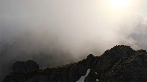 Thick clouds from the top of a mountain shrouded in mist, the sun shining Stock-Footage 235825281