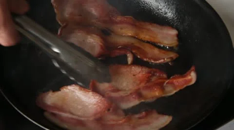 Thick cut bacon turned in frying pan Stock Footage 21528442