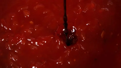 Thick dark sauce pouring into red tomato based soup Stock Footage 327577401