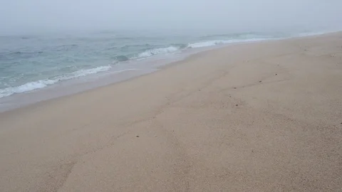 Thick, dense fog on the beach as waves break in slow motion on the sand Stock Footage 116183579